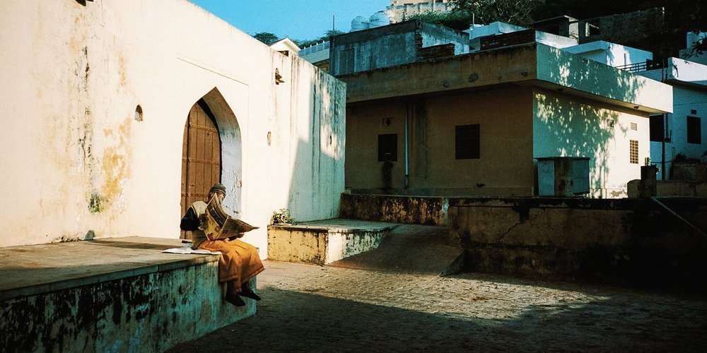 A man resting in a sunlit courtyard, India