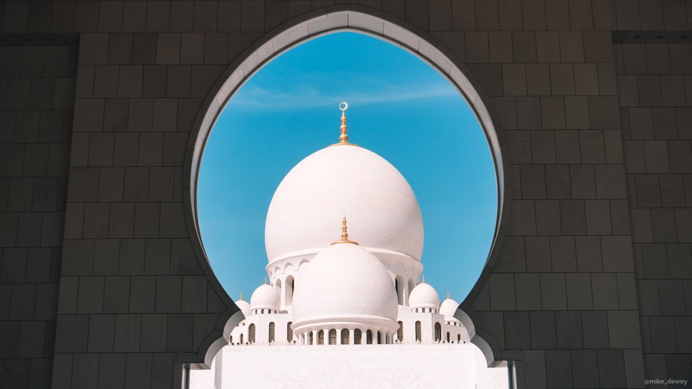 A white mosque dome framed by an arch
