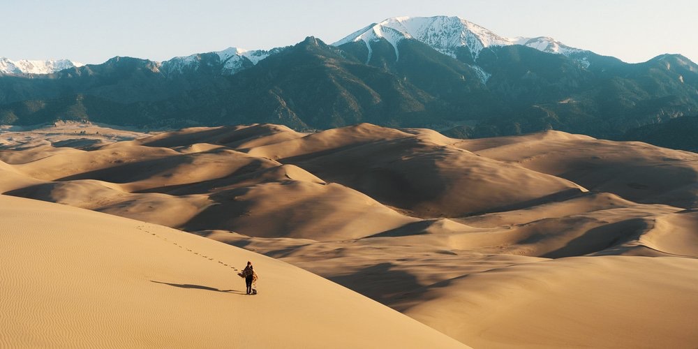 A lone hiker crossing sand dunes
