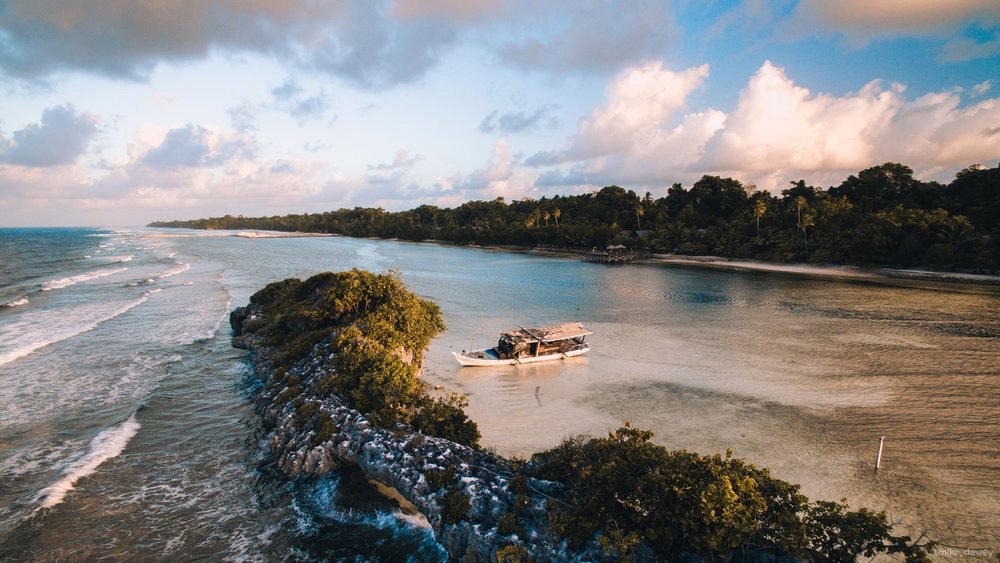 A boat off a rocky coastline at golden hour